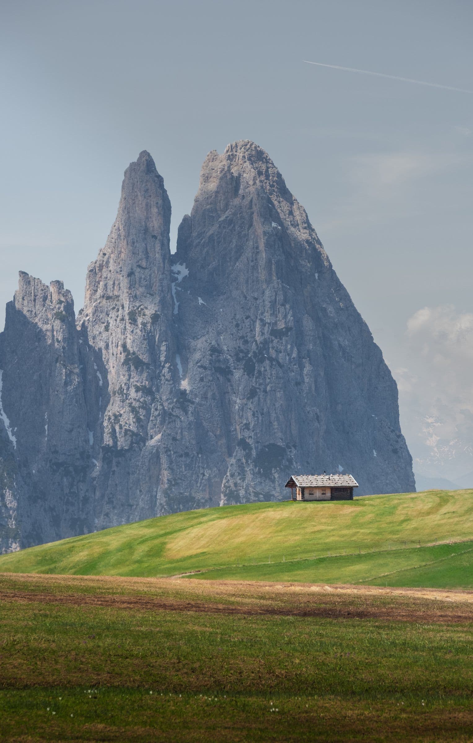 A lone hut on an alpine meadow below two peaks