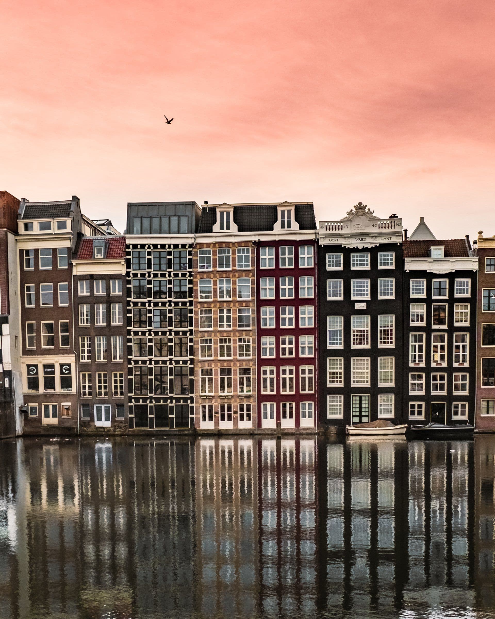 Canal houses on the Damrak under a pink evening sky